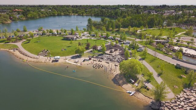 High altitude aerial drone footage of Esther Simplot Park in Boise, Idaho. Beautiful views of Esther&rsquo;s Pond with people enjoying the sandy beach and playing among the rock piles on a sunny day.