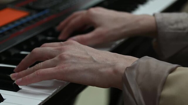 female pianist hands on black and white synthesizer keyboard, close-up view, young woman playing piano, professional musician