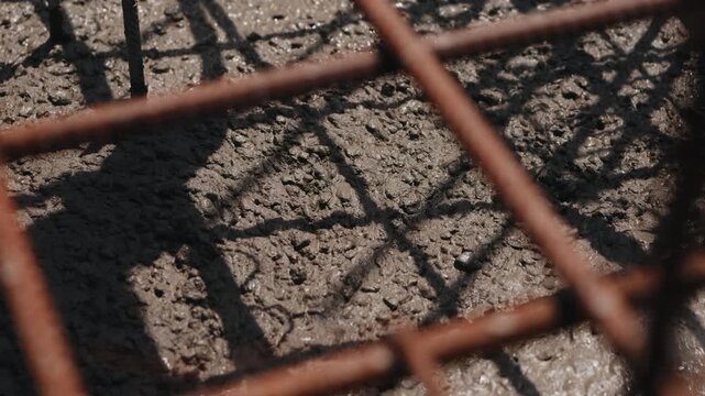 Concrete flowing beneath rebar during foundation pouring in slow motion