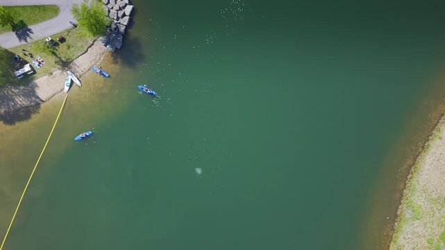 High altitude top-down drone shot of paddleboarders playing in the lagoon at Esther Simplot Park, Boise, Idaho. Colorful boards and people enjoying the calm water on a sunny day.