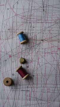 Spools of thread, thimble, tape measure against the background of a clothing pattern. Clothing cutting and sewing. Upcycling concept. Background for a creative atmosphere