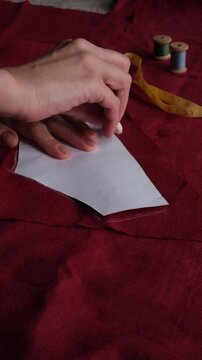 Cutting and stitching. A woman's hands trace a clothing pattern with chalk. Cutting out burgundy rough fabric. Clothing repair and sewing. 
