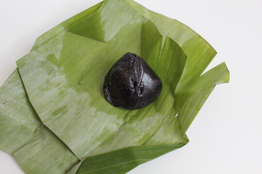 Kue bugis ketan hitam, traditional dessert from Indonesia, made from black glutinous rice flour dough, filled with grated coconut, wrapped in a banana leaf