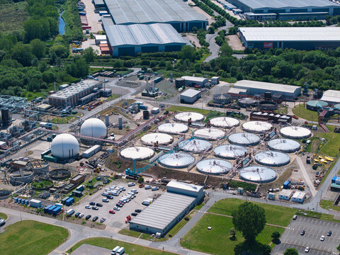 Aerial view of the Severn Trent Water Minworth facility featuring circular settling tanks and spherical gas holders in Birmingham, England, United Kingdom.