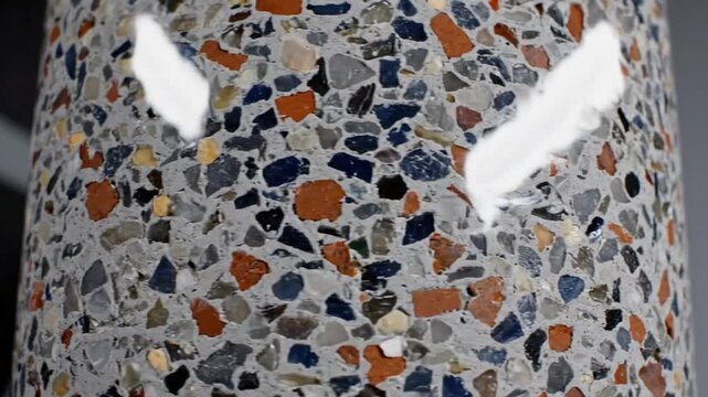Close-up of a textured surface with colorful fragments embedded in a gray background.