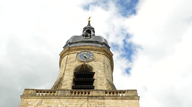 Historic church clock tower in Amiens with curved slate roof and cloudy sky