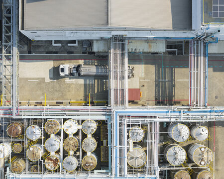 Aerial view of a synthetic resin chemical plant featuring industrial storage tanks, complex piping systems, and a parked tanker truck in Taiwan.