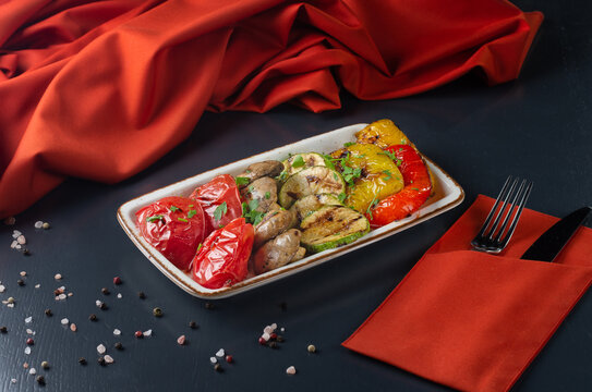 Grilled vegetables mix of grilled vegetables such as peppers, zucchini, tomatoes and mushrooms On a dark background.