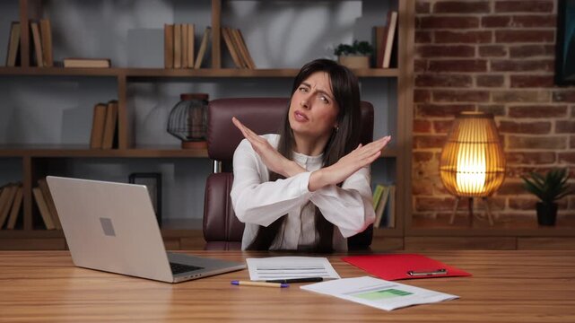 Business woman makes stop gesture with serious expression during meeting.