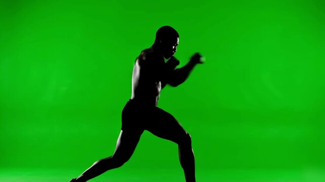 Silhouette of a Muscular Boxer in Fighting Stance Against Green Screen Background, Athletic Man Shadow Boxing for Sports Training
