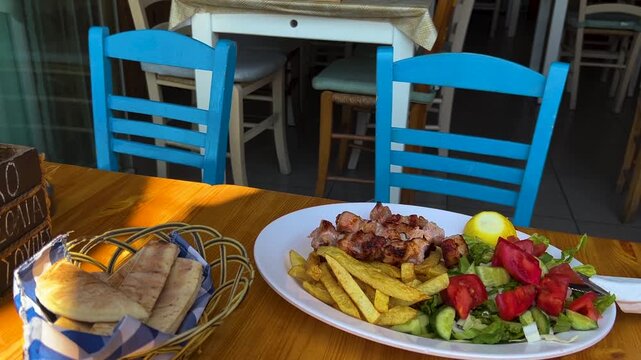 A table at a restaurant. Greek menu - pork souvlaki, vegetables, pita, French fries. Grilled meat in Cyprus.