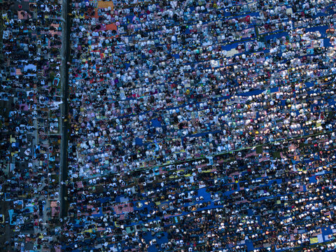 Aerial view of a large crowd of people gathered for Eid Al-Adha prayer on colorful mats in Garung, Kecamatan Kalikajar, Jawa Tengah, Indonesia.