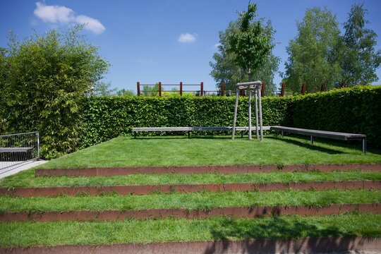 Terraced garden with striped lawn beds and a hedge in summer at Gardens of the World Berlin