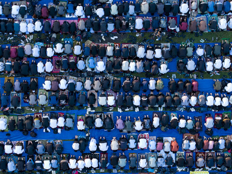 Aerial view of worshippers gathered in rows for Eid Al-Adha prayer on colorful prayer mats in Garung, Kecamatan Kalikajar, Jawa Tengah, Indonesia.