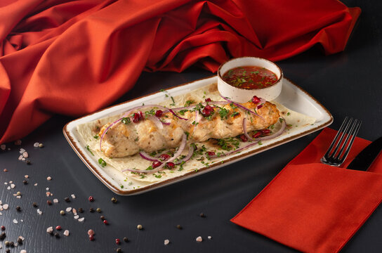 Lula-kebab of chicken with onions and hot red sauce. Around Lula-kebab onions, parsley, pomegranate.
