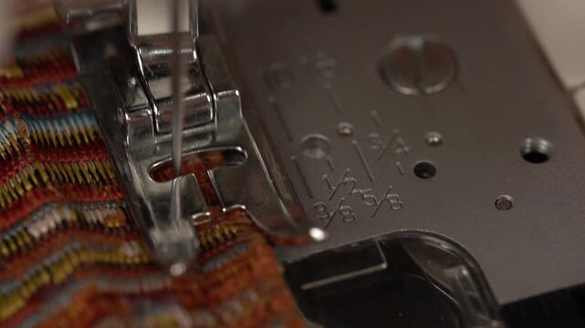 Close-up of a sewing machine needle and presser foot creating a zigzag stitch on fabric to finish the raw edge.