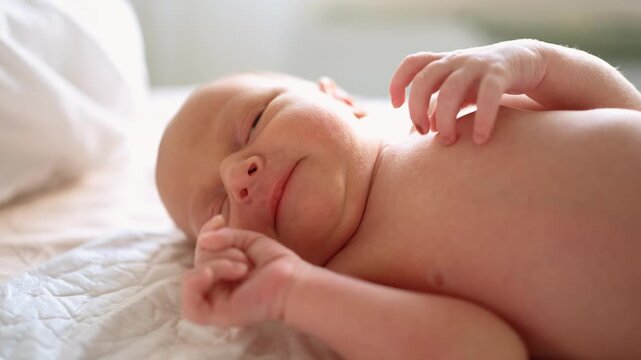 Delicate newborn baby with soft skin lying on a white blanket, moving tiny hands and feet before finally closing its eyes and falling into a deep and quiet sleep in a cozy bed