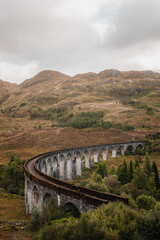 Naklejka premium The historic Glenfinnan Viaduct surrounded by lush green hills, Scottish Highlands