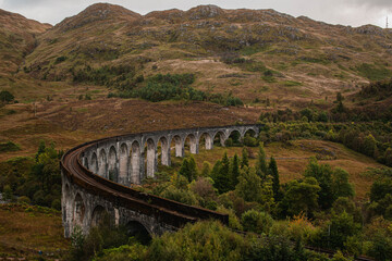 Naklejka premium The historic Glenfinnan Viaduct surrounded by lush green hills, Scottish Highlands