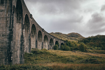 Naklejka premium The historic Glenfinnan Viaduct surrounded by lush green hills, Scottish Highlands