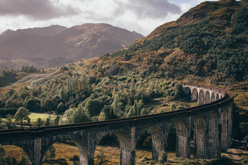 Naklejka premium The historic Glenfinnan Viaduct surrounded by lush green hills, Scottish Highlands