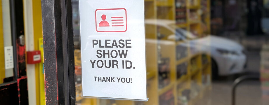 Please show your ID sign on a glass door, identity verification notice at shop entrance, age restriction policy for retail store