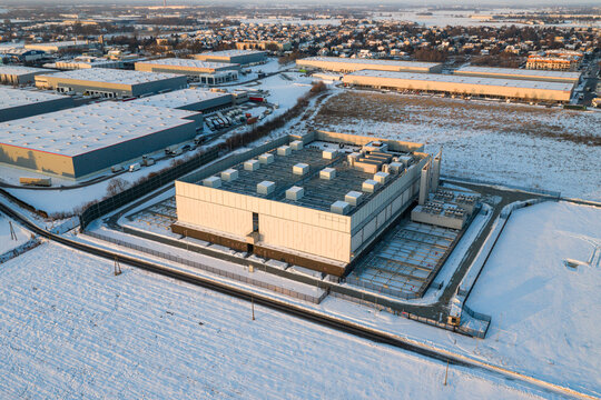 Aerial view of the Atman DC WAW-3 data center surrounded by snow-covered fields and industrial warehouses during winter in Duchnice, Wojewodztwo mazowieckie, Poland.