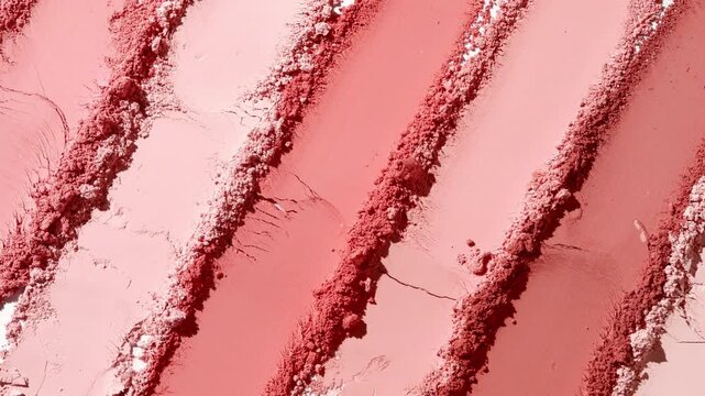 Overhead tight close-up shot of a water splash flowing over a red parallel palette knife trail powder surface illuminated by orbiting light that casts dynamic shadows | Blush commercial concept