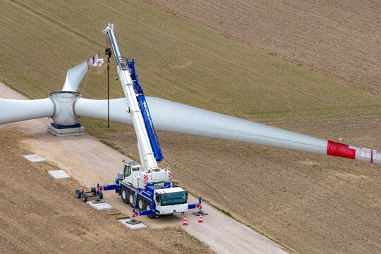 Aerial view of a large mobile crane assembling a massive wind turbine blade in an open field Zielona, Masovian Voivodeship, Poland.