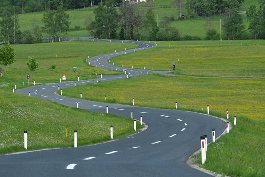 Empty winding road through green spring meadows in the rural countryside of Styria, Austria