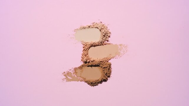 Top perspective capture of three skin tone color aligned streaks of loose powder | On a rosy pink background illuminated by orbiting directional light