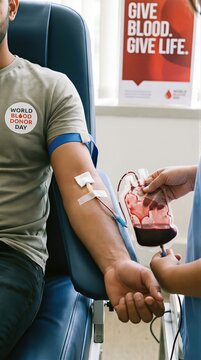 Man donating blood in clinic to support World Blood Donor Day. Medical nurse collecting blood in bag from volunteer donor for transfusion. Healthcare awareness, lifesaving charity concept.