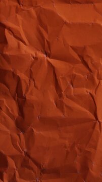 Vertical stop-motion animation of neon orange wrinkled paper. Seamless loop for warm mobile-friendly backgrounds and creative vertical content.