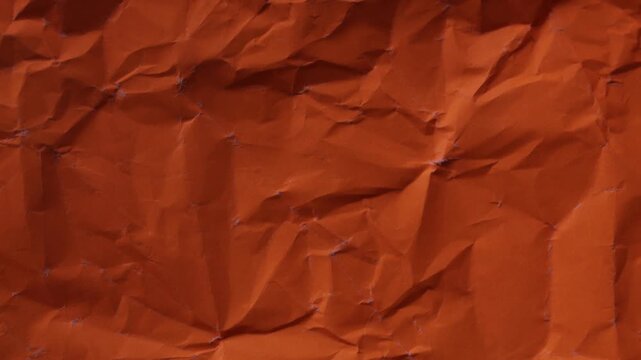 Vibrant orange wrinkled paper texture seamless loop. Warm stop-motion animation for creative video overlays and artistic backgrounds.