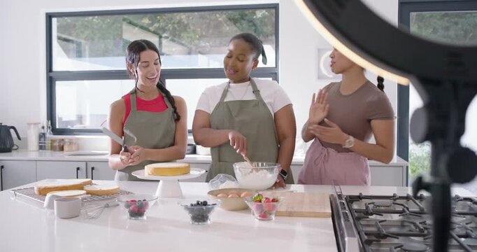 Diverse women ringlight phone recording, filming, stirring bowl, stacking cake in kitchen for demo