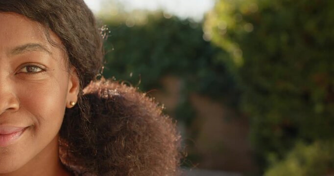 Camera shifting African woman turning smiling, laughing in garden, stud earring shining, copy space