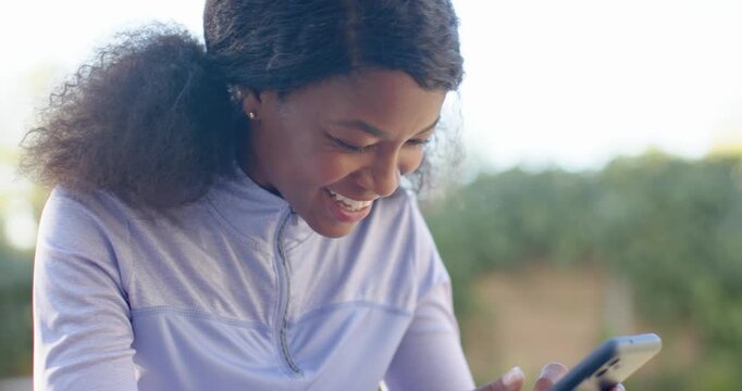 African American woman seeing funny message, laughing and tapping phone by pool with white watch