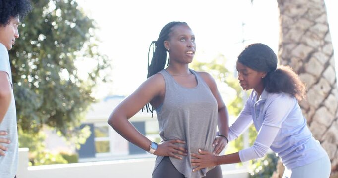 African American coach coming to client in grey tank, checking hip alignment, watch visible