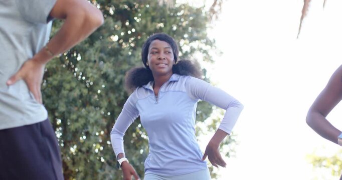 African American women initiating arm sweep, moving in sync on wooden deck with smartwatch, warming