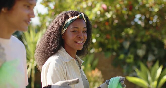 African couple starting gardening walking and talking in sunny yard and woman holding green gloves