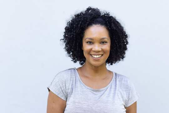 African American woman smiling and wearing grey tee with dark headband in studio facing camera