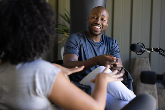 African American co-hosts sitting facing each other in home studio with microphone on boom arm