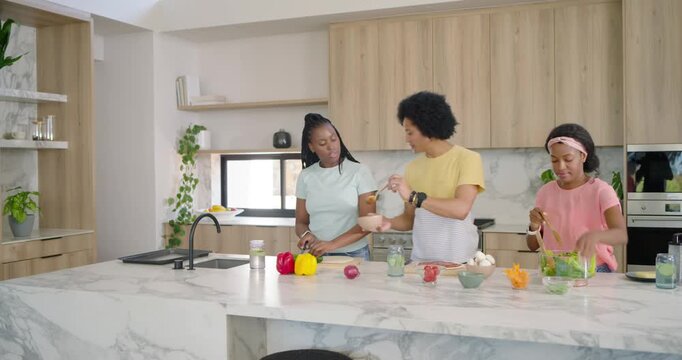 African American family chopping, mixing and tossing salad at marble island preparing dinner