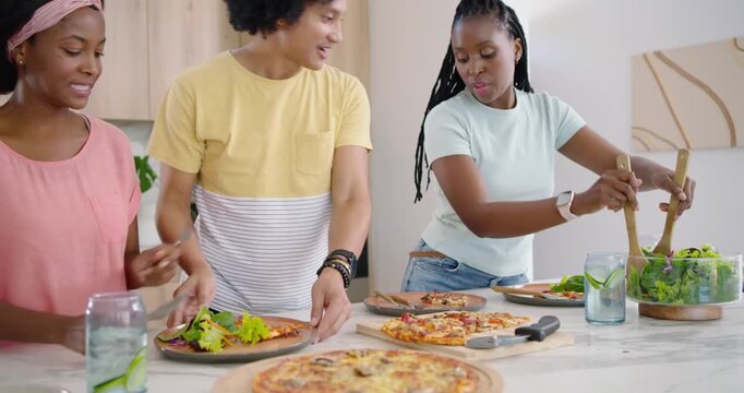 African American friends spotting pizza, moving to island, cutting pizza and tossing salad to share