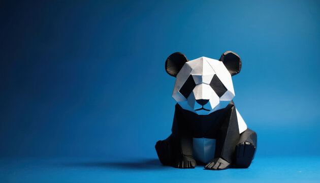 Origami panda figure sits against bright blue background. Geometric black and white paper craft animal is minimalist and playful. Artistic design evokes zoo or wildlife themes.