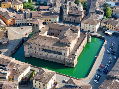 Aerial view of Fontanellato Castle with its distinctive green water moat surrounded by historic town buildings and terracotta rooftops in Fontanellato, Emilia-Romagna, Italy.