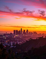 Obraz premium A vibrant sunset paints the sky over a sprawling cityscape nestled amongst rolling hills.
