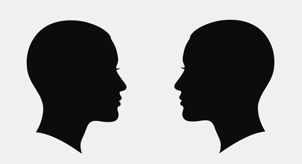 Fototapeta premium Two identical black silhouettes of human heads facing each other representing communication or psychology concepts.