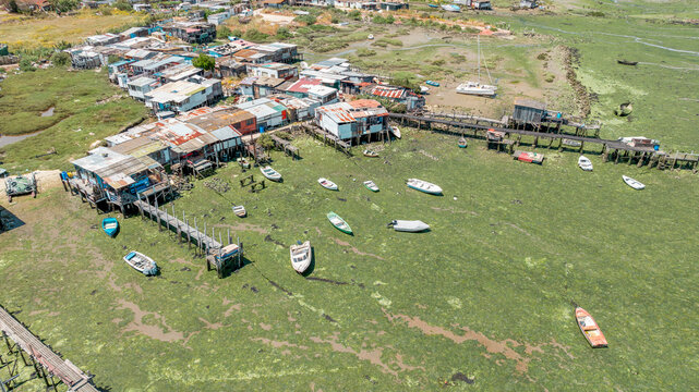 Aerial view nearby Parque da Moita featuring traditional stilt houses and fishing boats scattered across a green marshy landscape in Lavradio, Setubal, Portugal.