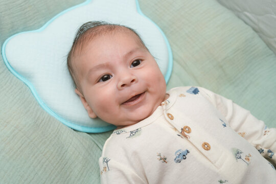 Beb&eacute; latino feliz de 3 meses sonriendo acostado en su cuna